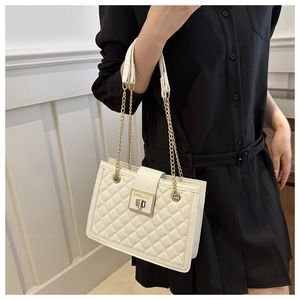 Macro shot of white quilted leather bag with elegant golden clasp and chain strap