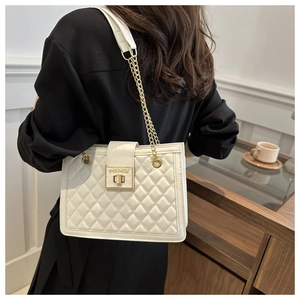 Detailed close-up of white quilted tote bag featuring a gold chain strap and metal lock