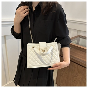 Detail of white quilted handbag featuring gold chain strap and metal turn-lock closure