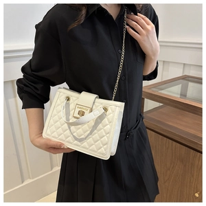 Detail of white quilted handbag with a gold metal rectangular clasp and chain strap