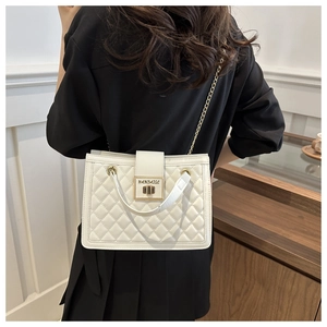 Detail of white quilted handbag featuring gold twist lock and elegant metal chain strap