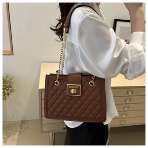Detail of brown quilted shoulder bag with gold chain strap and turn-lock closure