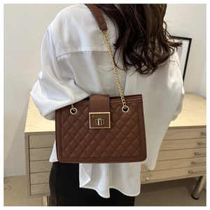 Close-up of brown quilted leather bag featuring a gold twist lock and chain strap