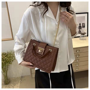 Close-up of brown quilted chain shoulder bag with gold metal buckle and leather handle