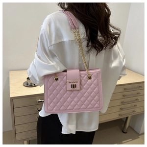 Close-up of pink quilted chain shoulder bag with gold metal lock and leather texture