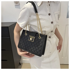 Detail of black quilted leather shoulder bag featuring a gold latch and chain strap