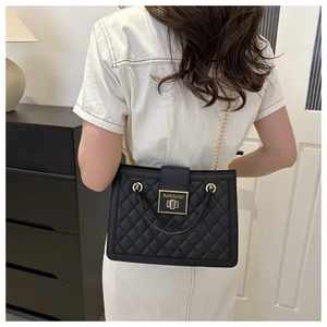 Close-up of quilted black leather bag with gold hardware lock and chain strap detail