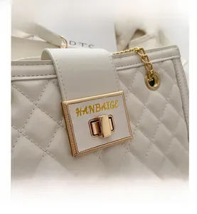 Detailed macro view of white quilted faux leather texture with gold chain and metal lock
