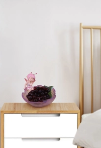 Detail of lavender fruit tray with fairy figurine storage on wooden bedside table