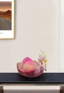 Close-up of a resin flower fruit tray with a fairy figurine on a marble table