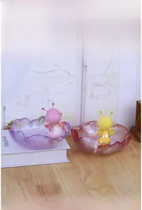Close-up of petal-shaped storage bowls in purple and pink with cute fairy figurines