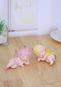 Close-up of cute sleeping fairy figurines in pink and yellow for desktop decor