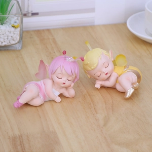 Cute sleeping fairy baby resin ornaments with wings on light wood desktop background