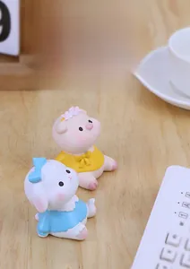 Cute resin pig and rabbit ornaments in yellow and blue dresses on a wooden desk