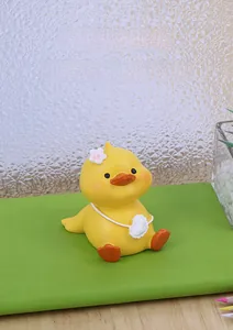 Close-up of a cute yellow resin duck figurine with a white cloud bag on a green notebook
