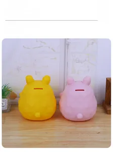 Detail of yellow and pink enamel rabbit piggy banks with coin slots on a wooden desk