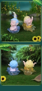 Close-up of fairy doll figurines with intricate wings and floral base in a forest scene