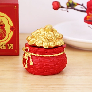 Close-up of red resin money bag ornament with gold ingots and a festive gift box