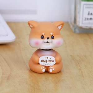 Cute Shiba Inu bobblehead ornament holding 'Keep Smiling' sign on a wooden desk