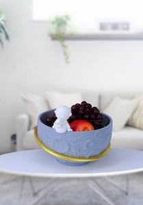 Detail of moon-themed astronaut snack bowl with crater texture and gold planetary rings
