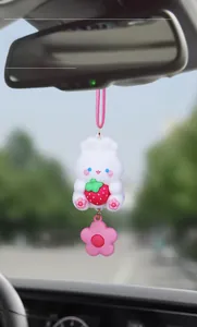Close-up of a cute white bunny car pendant with strawberry and pink flower detail