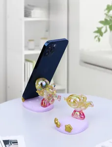 Macro shot of colorful resin astronaut phone stands with gold star on purple base