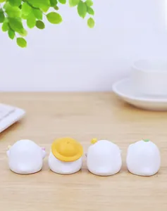 Four cute white resin duck figurines with yellow hats on a desk near a keyboard
