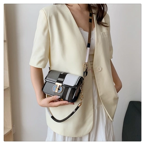 Detail of checkered crossbody bag with T-shaped buckle worn with a beige blazer