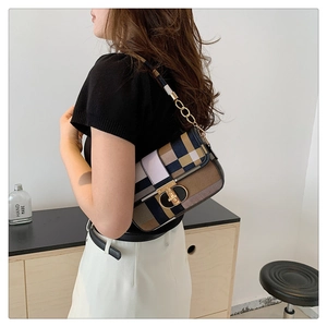 Detail of color-block plaid handbag with gold T-lock and chain strap on shoulder