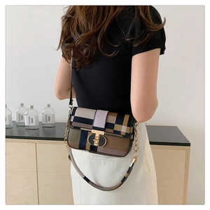 Detail of color-block plaid crossbody bag featuring a golden rotary lock and chain strap