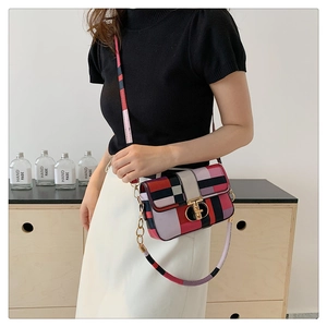 Detail of color-block plaid square bag showing gold ring twist lock and patchwork strap