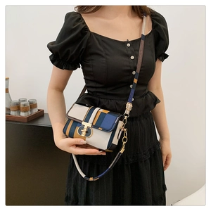 Detail of color-block plaid crossbody bag with circular gold buckle and vintage flap design