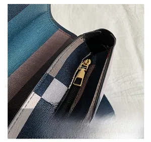 Detailed macro view of the golden metal zipper closure on the plaid handbag
