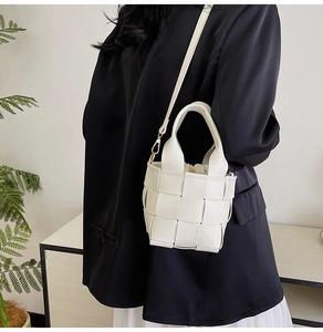 Gros plan du sac seau tissé blanc avec bandoulière en cuir et pochette intérieure