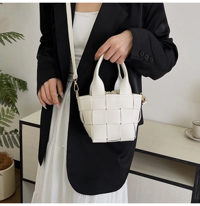 Détail du sac seau tissé blanc avec poignée et doublure à cordon porté par un modèle