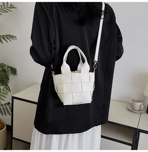 Vue détaillée d'un sac à main blanc tressé avec poignée ronde porté par un mannequin