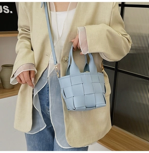 Détail du sac seau en cuir tressé bleu clair avec d'élégantes ferrures en métal doré