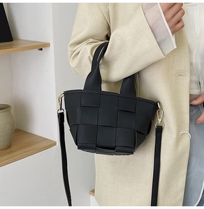 Détail du sac bandoulière tissé noir avec texture en cuir mat et finitions dorées