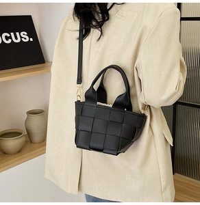 Gros plan sur la texture en cuir tressé noir d'un sac à bandoulière avec boucle métal