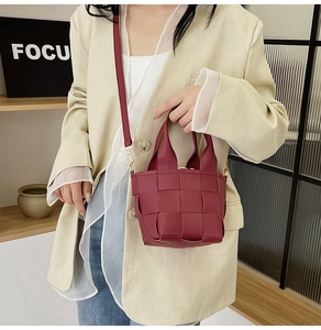 Détail de la texture tissée rouge foncé d'un mini sac porté avec un blazer beige