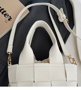 Détail d'un sac à main beige en cuir tressé avec texture grillagée et pochette intérieure