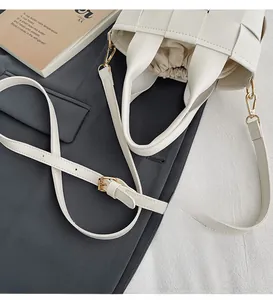 Gros plan du sac tissé en cuir blanc avec finitions dorées et bandoulière réglable
