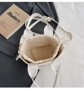 Détail du sac seau tressé crème avec doublure en toile et bandoulières amovibles