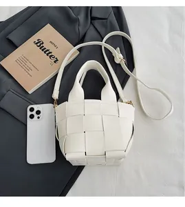 Gros plan d'un sac seau tressé blanc avec tissage en cuir large et détails dorés brillants