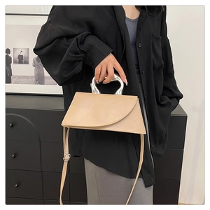 Detail der minimalistischen beigen Tasche mit einzigartigem silbernem Metallgriff und Klappe
