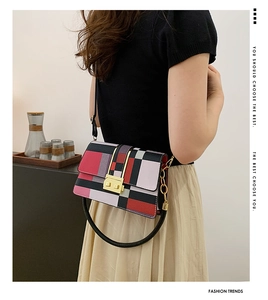 Detail of color-block crossbody bag with gold lock and circular top handle worn by model