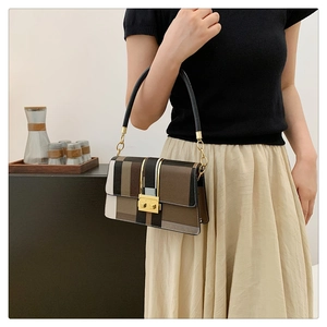 Detail of trendy color-block crossbody bag with gold lock and chain strap on a model