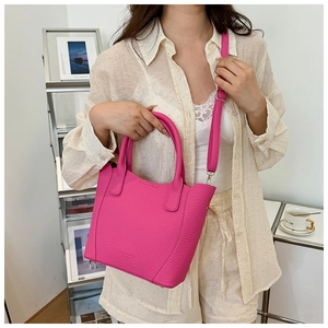 Mannequin portant un sac seau rose en cuir grainé avec poignées et bandoulière réglable