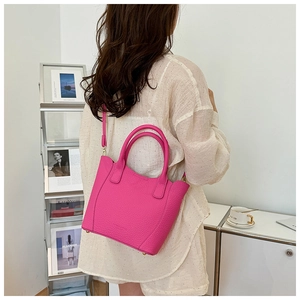 Détail du sac seau fuchsia en cuir avec poignées et une fine bandoulière réglable