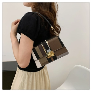 Detail view of contrast color crossbody bag featuring golden hardware and metallic twist lock